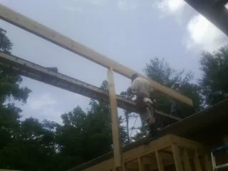 Carpenter setting a ridge beam over a new addition frame — Ice Dam Removal by Roofing Brothers in Manassas