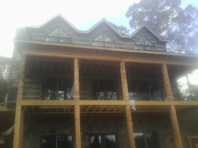 Dormers and porch framing on a large log home under construction — Roof Coating work by our crew in Manassas