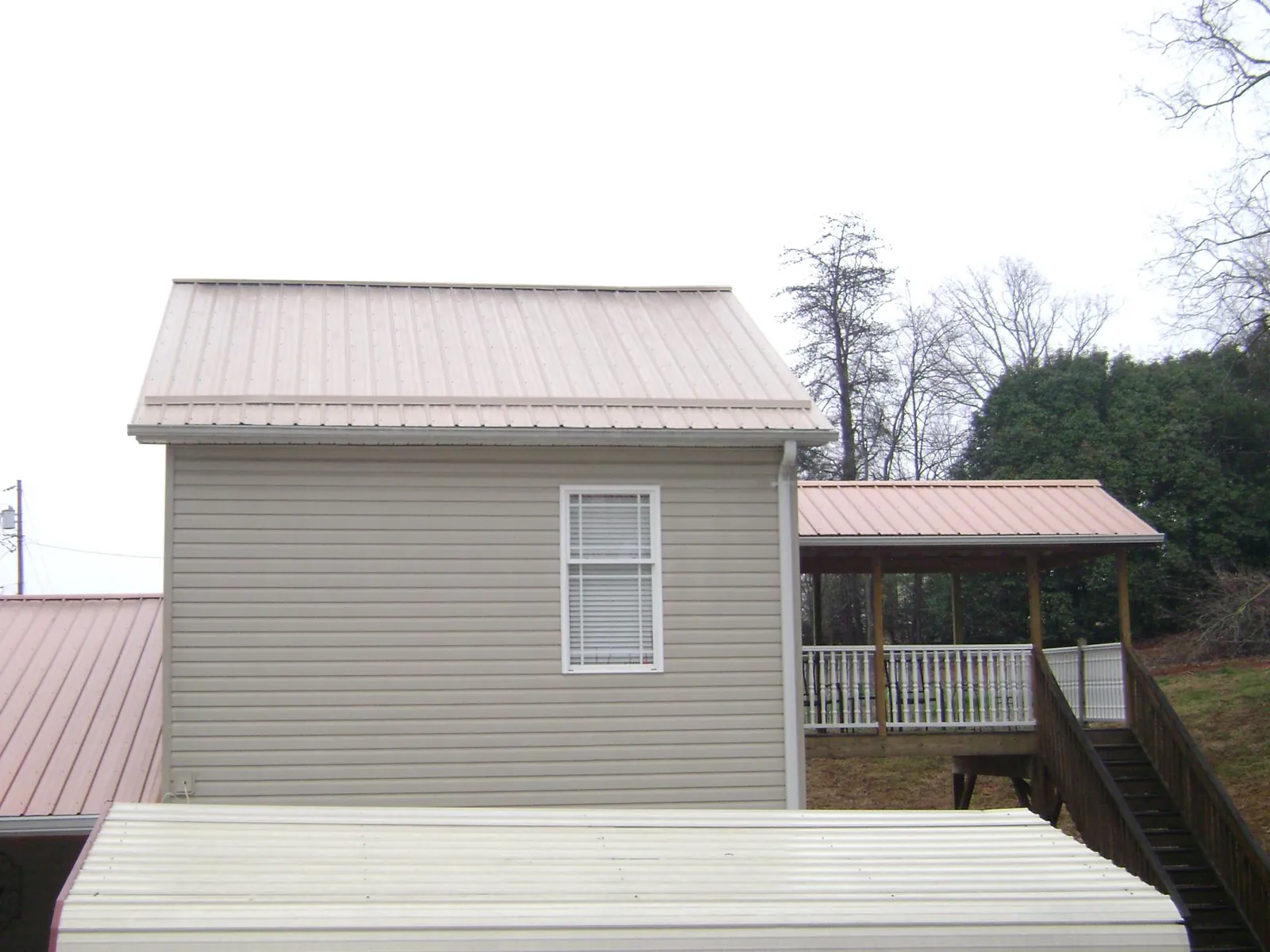 Tan metal roofs on a two story addition and attached porch, from a Roof Replacement job in Manassas