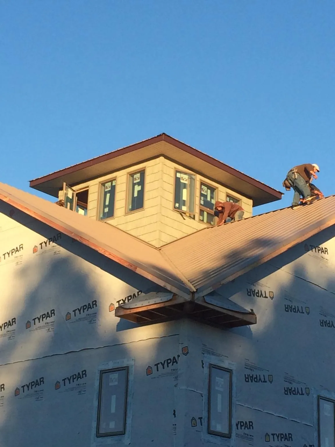 Roofers working around a rooftop cupola on a new metal roof at sunset — Roof Waterproofing in Manassas by Roofing Brothers